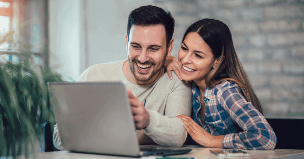 A man and woman sit at a table while looking at a computer and learning about the benefits of bundling Internet and phone with HTC