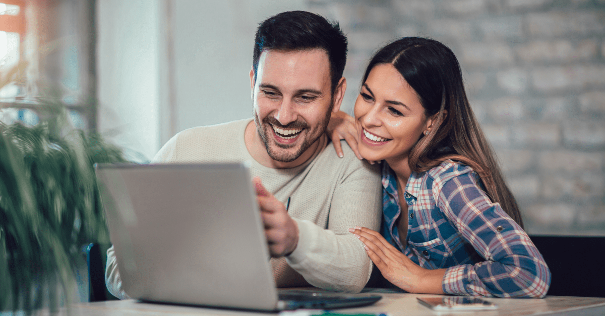 A man and woman sit at a table while looking at a computer and learning about the benefits of bundling Internet and phone with HTC