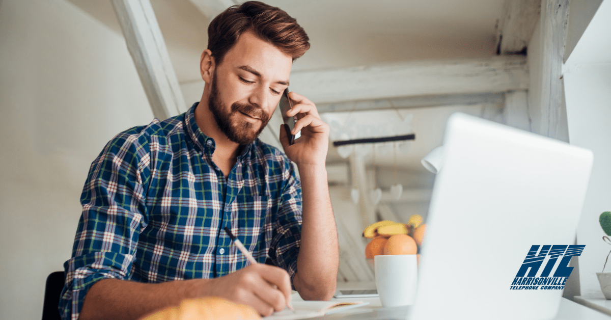 Business man considers a business Internet and phone bundle from HTC while talking on the phone and looking at his computer