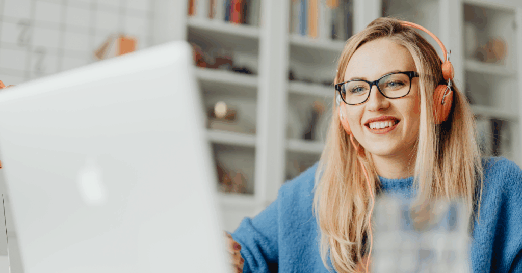 Woman smiles as she listens to headphones while using a laptop, likely thanks to consistent download speeds
