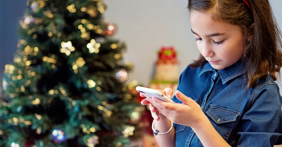 Child uses phone in front of a Christmas tree using fast and reliable fiber internet from HTC