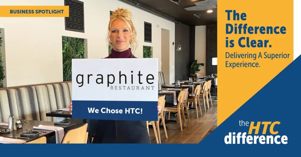 Amber from Graphite Restaurant holds a sign with the Graphite Restaurant logo and the words "We Chose HTC."