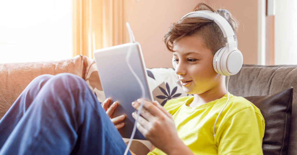 Child home for the summer smiles while watching a video on a tablet as they are connected with HTC Advanced WiFI