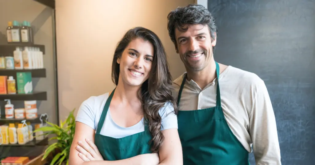 A man and woman working with local businesses pose for the camera and smile.