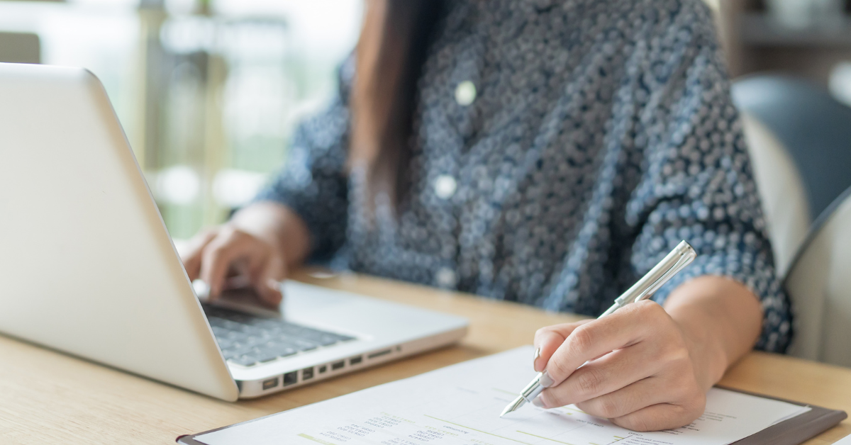Person sitting at a laptop on a desk, making a list of reasons why choosing a local Internet provider is beneficial.
