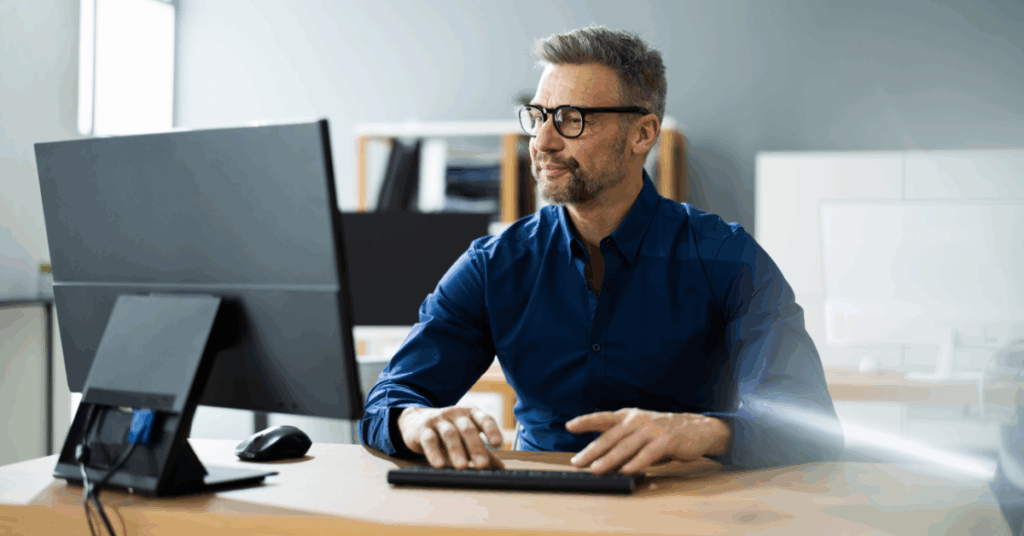 Businessman sitting at a desk with a computer, using Internet after making the switch to HTC Business Services